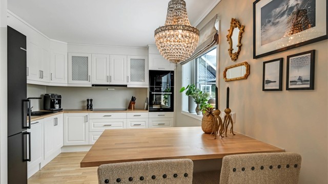 Kjøkkenet fremstår som stilrent og funksjonelt med innredning i profilerte fronter og benkeplate i heltre eik.