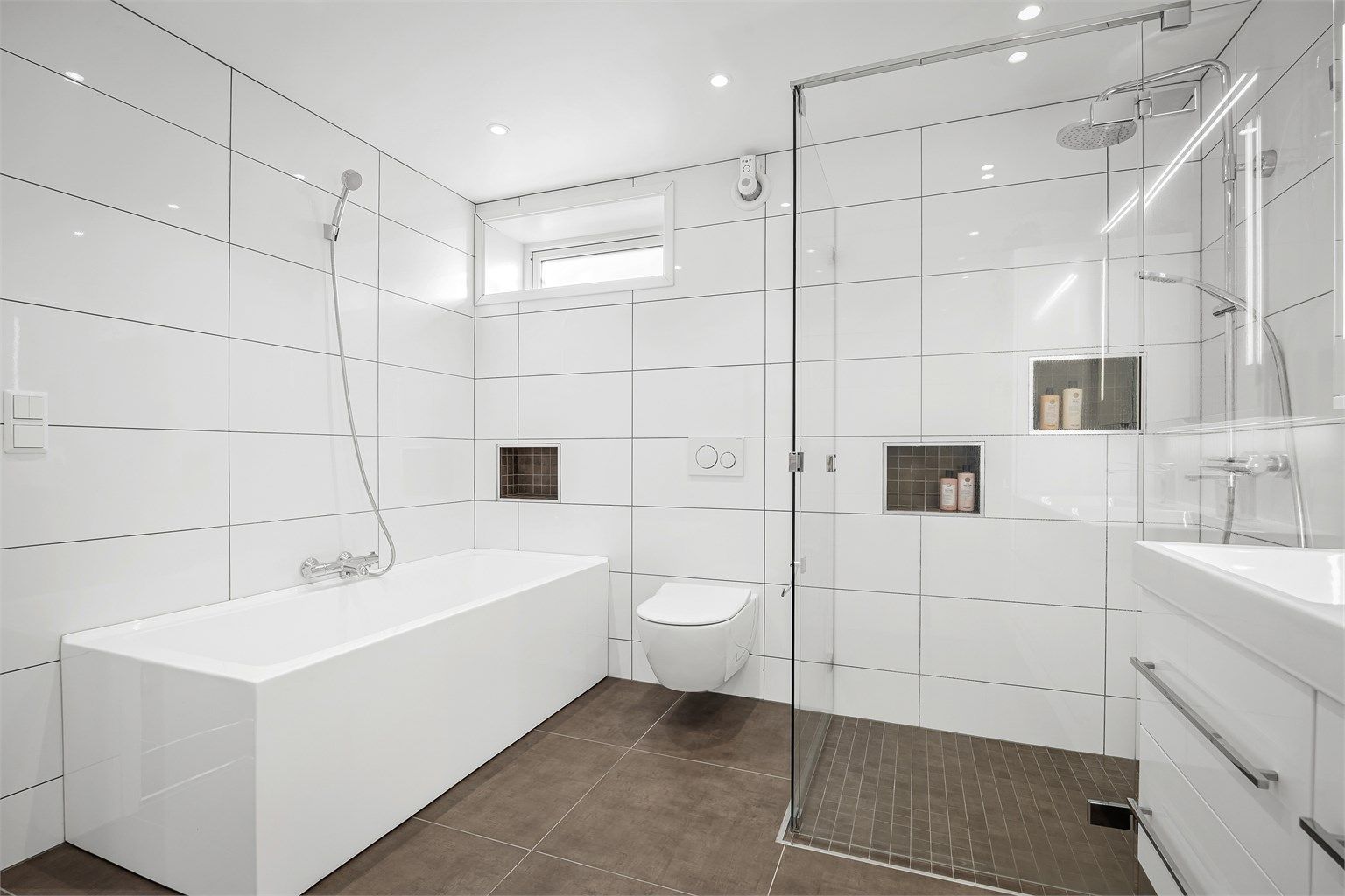 Rommet er utstyrt med både badekar og en romslig dusj med glassvegger.