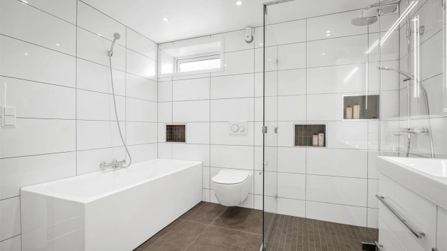 Rommet er utstyrt med både badekar og en romslig dusj med glassvegger.