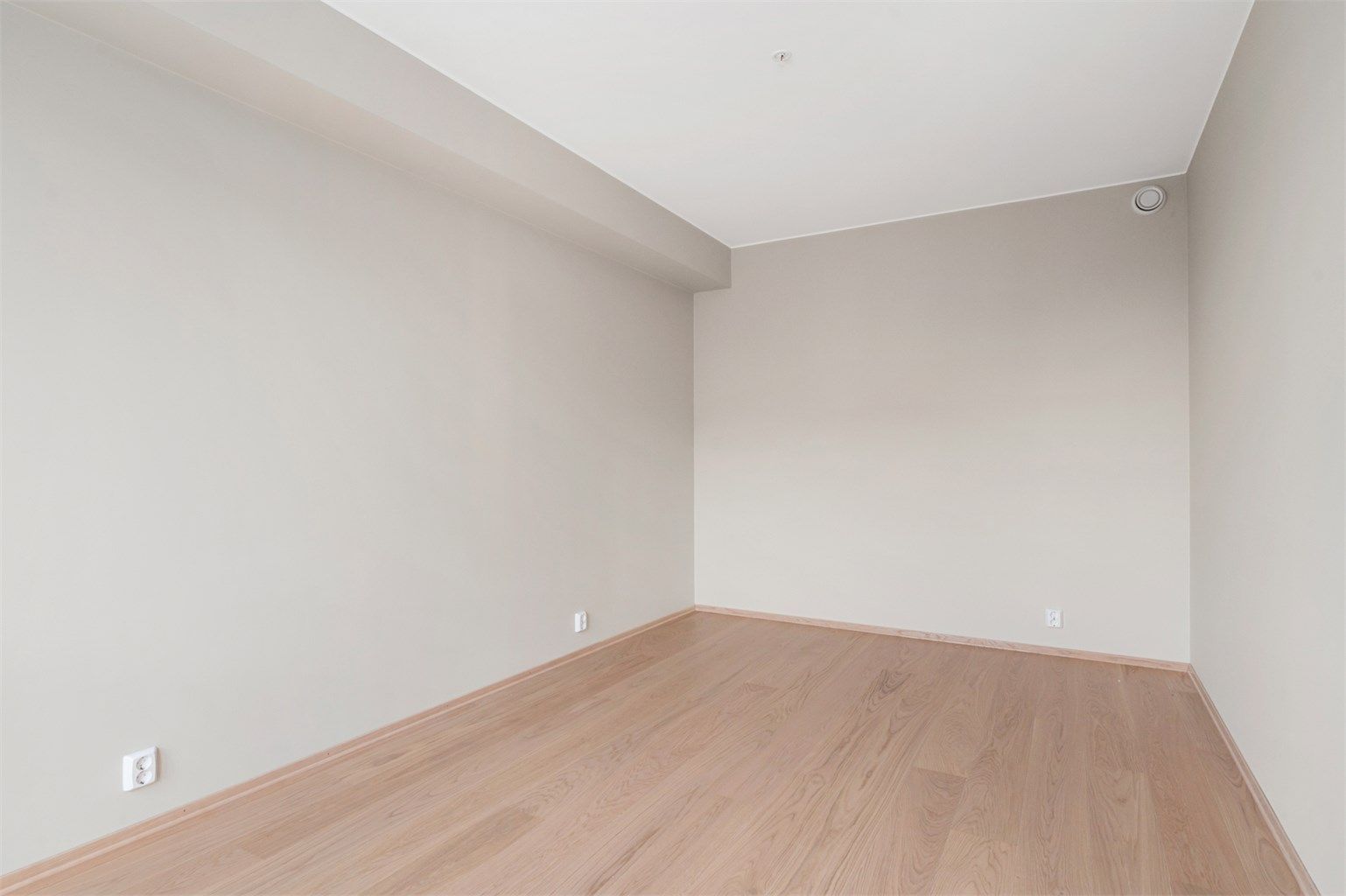 Gulv av parkett og malte flater på vegger og i himling. 