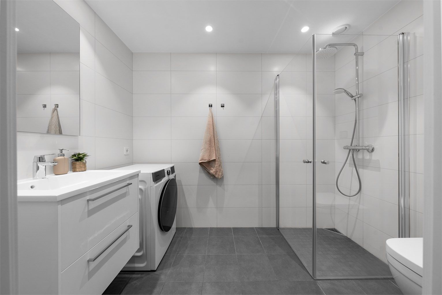 Moderne, flislagt bad fra byggeåret med elektriske varmekabler i gulv. Det er opplegg for vaskemaskin.