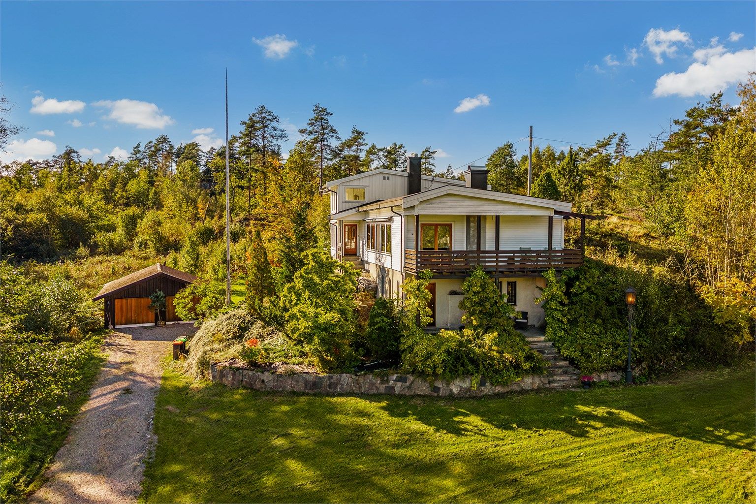 Natursteinsmur, prydbusker og blomsterbed danner en ramme omkring boligen.