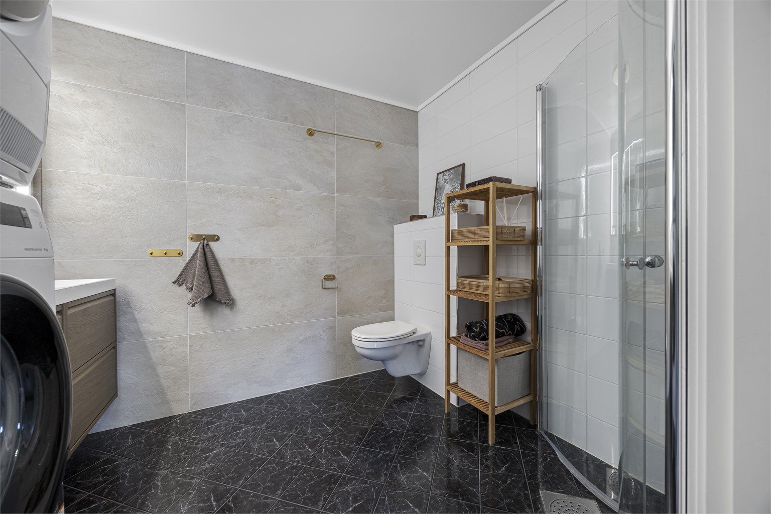 Rommet er praktisk innredet med dusjhjørne, vegghengt toalett og opplegg for vaskemaskin.