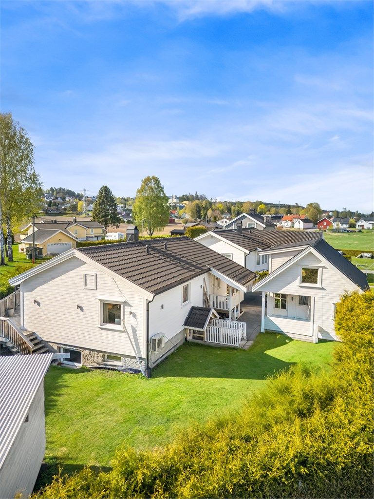 Tilnærmet flat tomt som er opparbeidet med singlet innkjørsel og grøntarealer, herunder gressplen samt hekk.