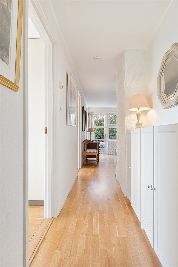 Innvendig trapp av tre med rekkverk av tre fra hall i første etasje ned til gang i underetasje.