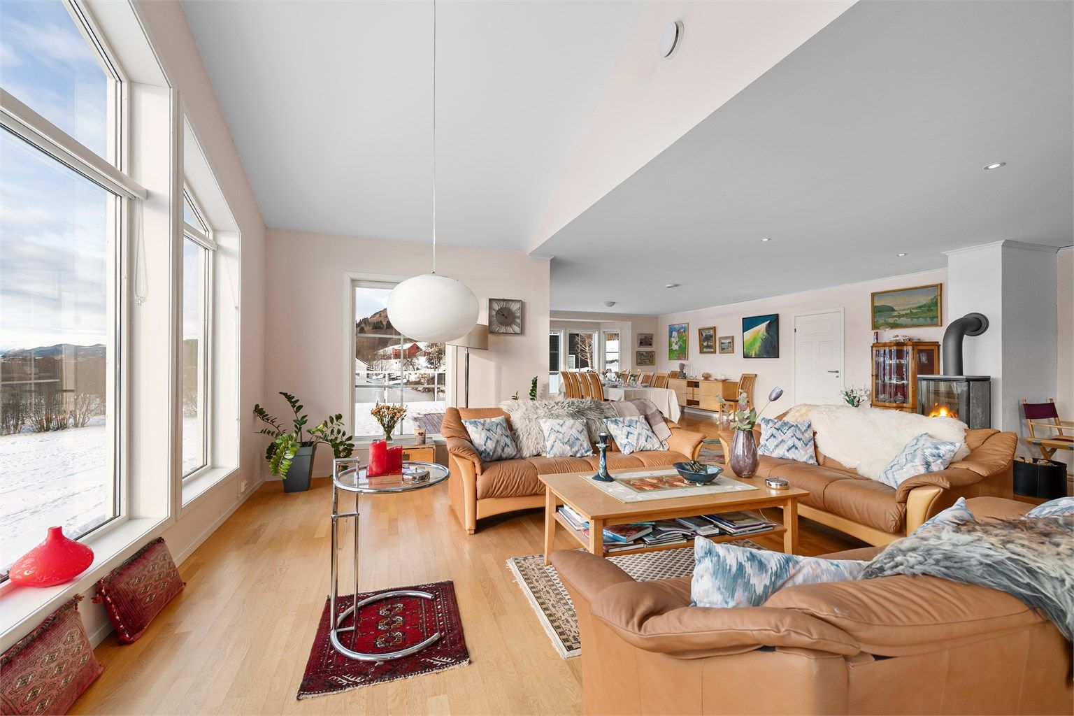 Gjennomgående parkettgulv og lyse overflater binder de ulike sonene i stuen sammen.