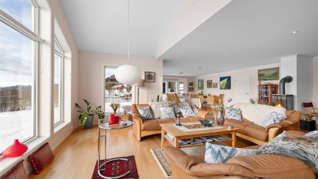 Gjennomgående parkettgulv og lyse overflater binder de ulike sonene i stuen sammen.