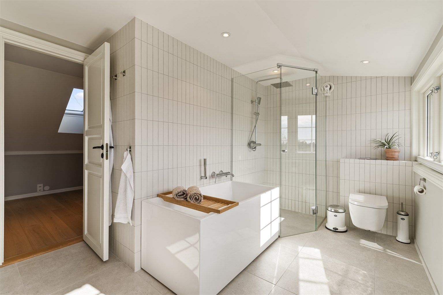 Rommet er utstyrt med både badekar og et dusjhjørne med regnfallsdusj. Toalettet er vegghengt.