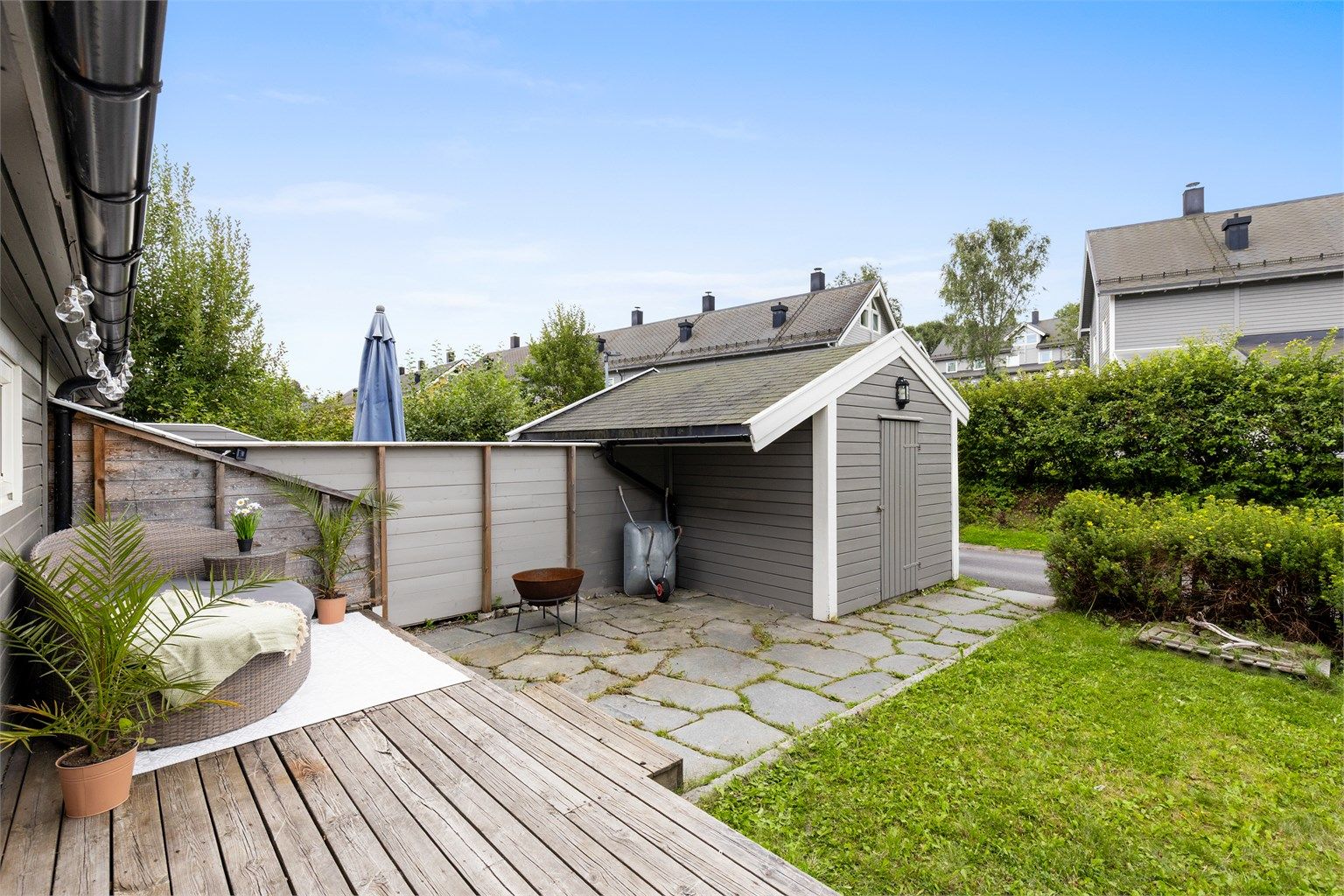 Inngangspartiet er pent opparbeidet med beplantinger og plen, med en utebod til oppbevaring av utstyr.