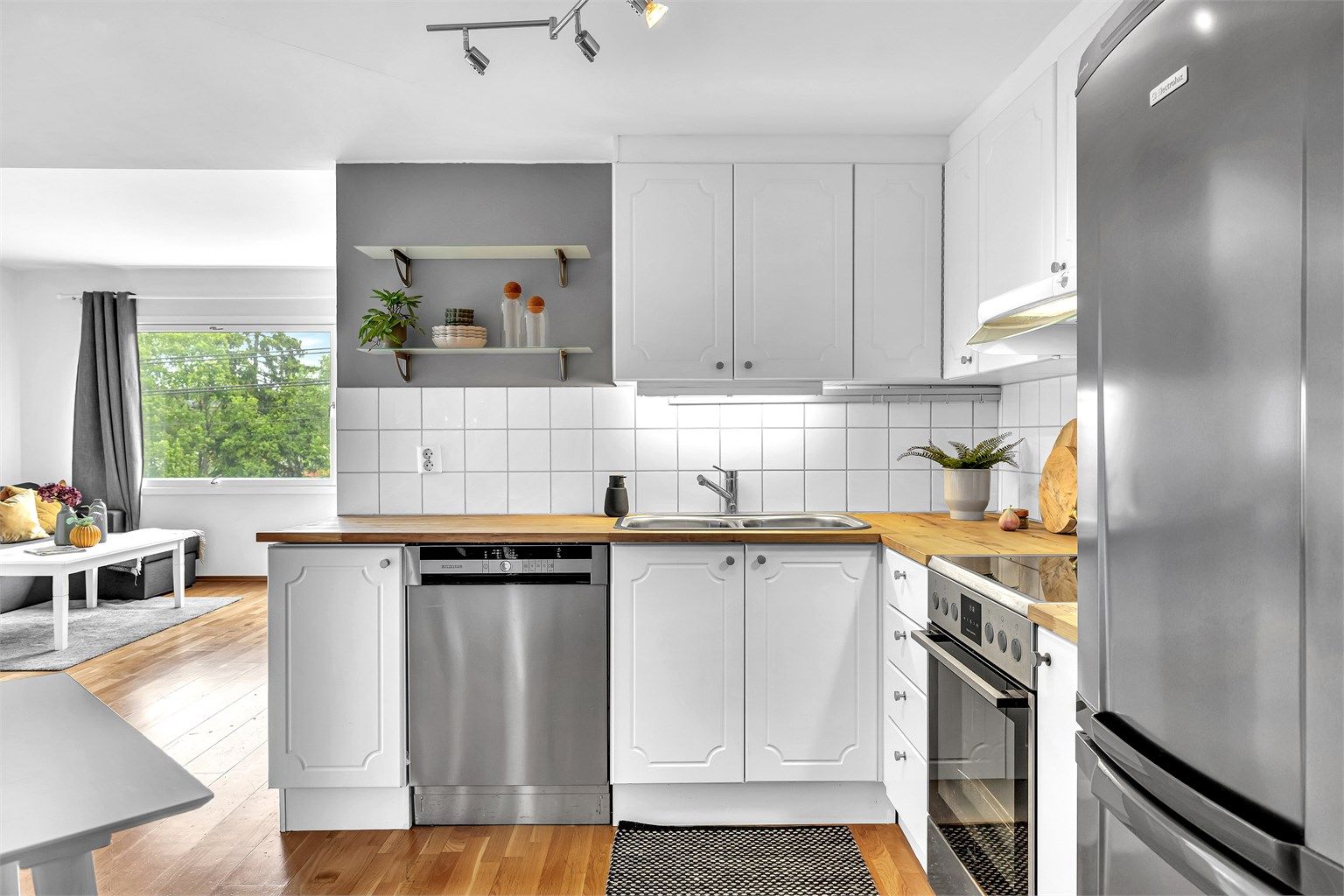 Fliser over benkeplate og dobbel stikkontakt på vegg samt dobbel stikkontakt i lysarmatur. Frittstående komfyr er plassert i nisje. Innebygget oppvaskmaskin.