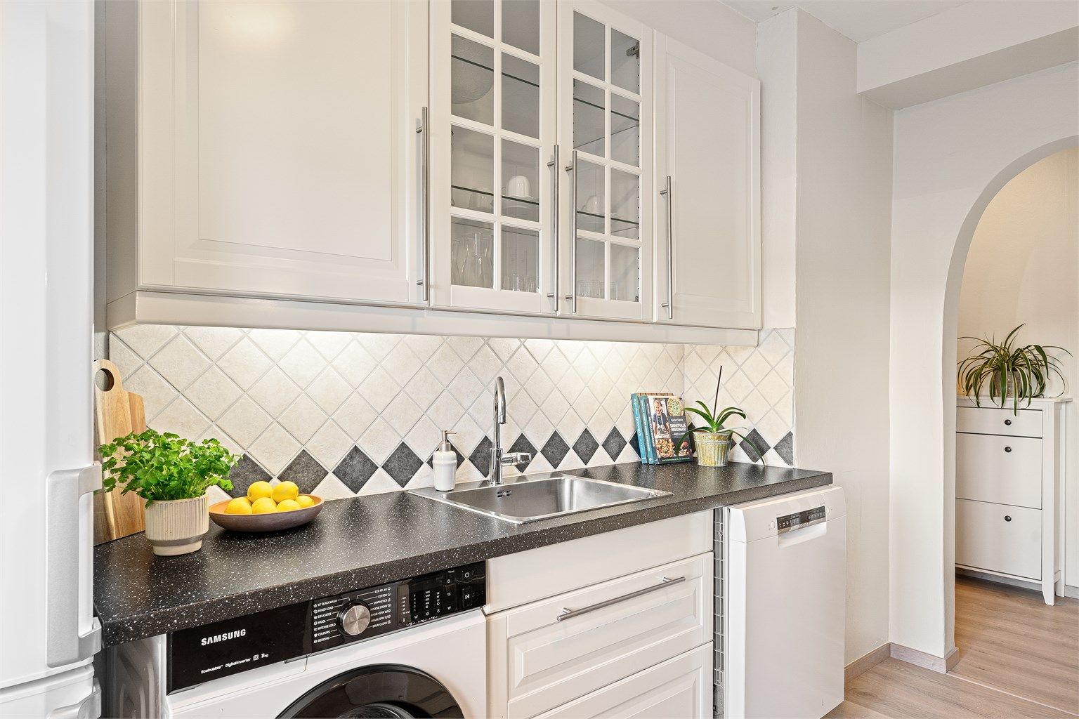 Kjøkkenet ligger naturlig tilbaketrukket fra stuen og har klassiske fronter og flislagt vegg over benk - som gir et tidløst og velholdt uttrykk.