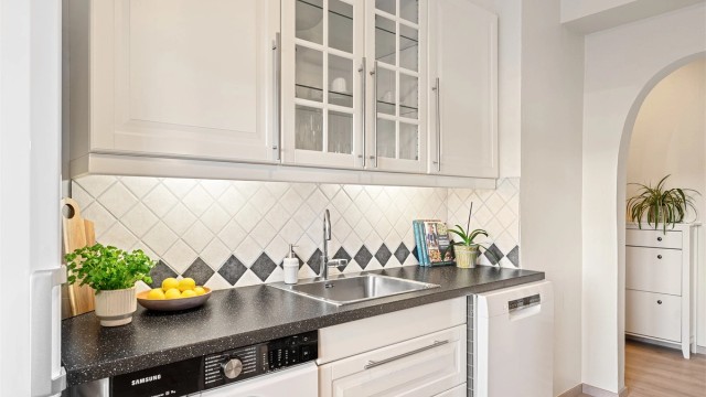 Kjøkkenet ligger naturlig tilbaketrukket fra stuen og har klassiske fronter og flislagt vegg over benk - som gir et tidløst og velholdt uttrykk.