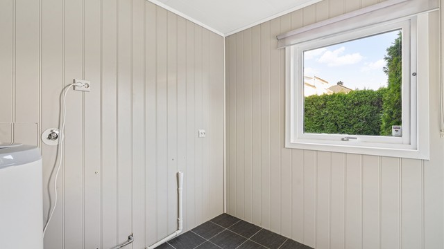 Separat vaskerom med flislagt gulv, sluk og opplegg for vaskemaskin.