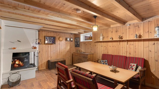 Rom innredet som kjellerstue med en koselig åpen peis i hjørnet som gir ekstra varme til rommet