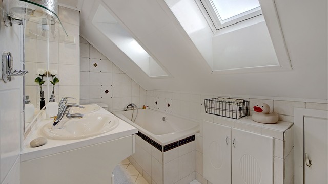 Bad - i loftsetasje - flislagt gulv med gulvvarme - baderomsinnredning (dobbel servant med underskap og speil) - innmurt badekar - toalett