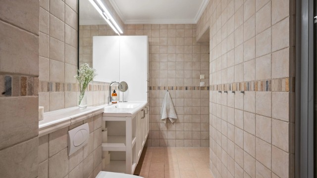 Badet er innredet med vegghengt toalett, servant med underskap og innfelte LED-downlights i taket.