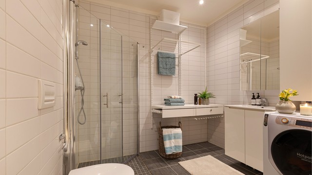 Badet i loftetasje har lyse farger, vegghengt toalett, lekker vask og innfellbare glassdører. Speilskap over vask og downlights i himling.