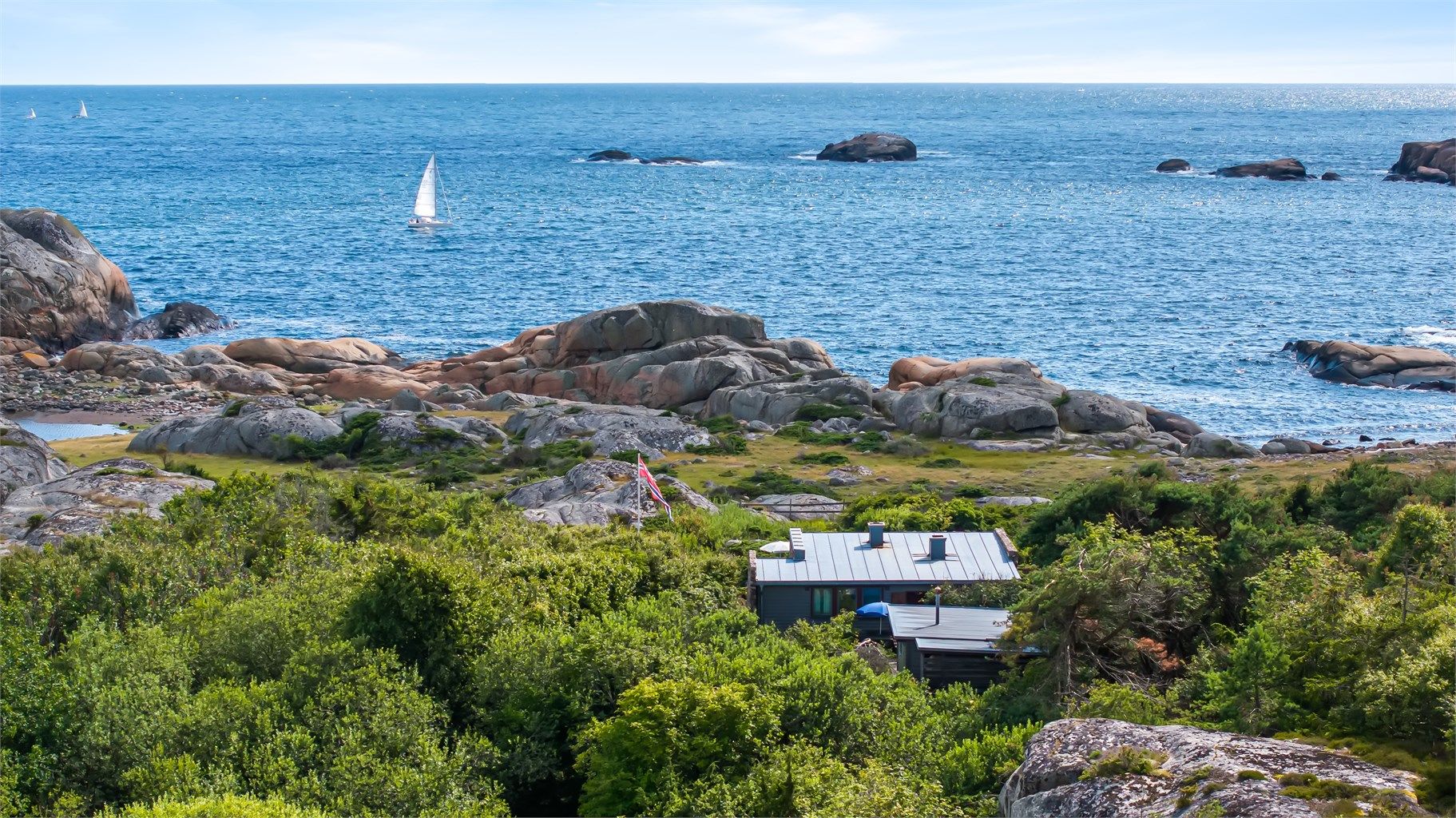 Hytta er omkranset av stille skog, svaberg og glitrende sjø – med utsikt hele veien ut mot havgapet og mektige Skagerrak. 