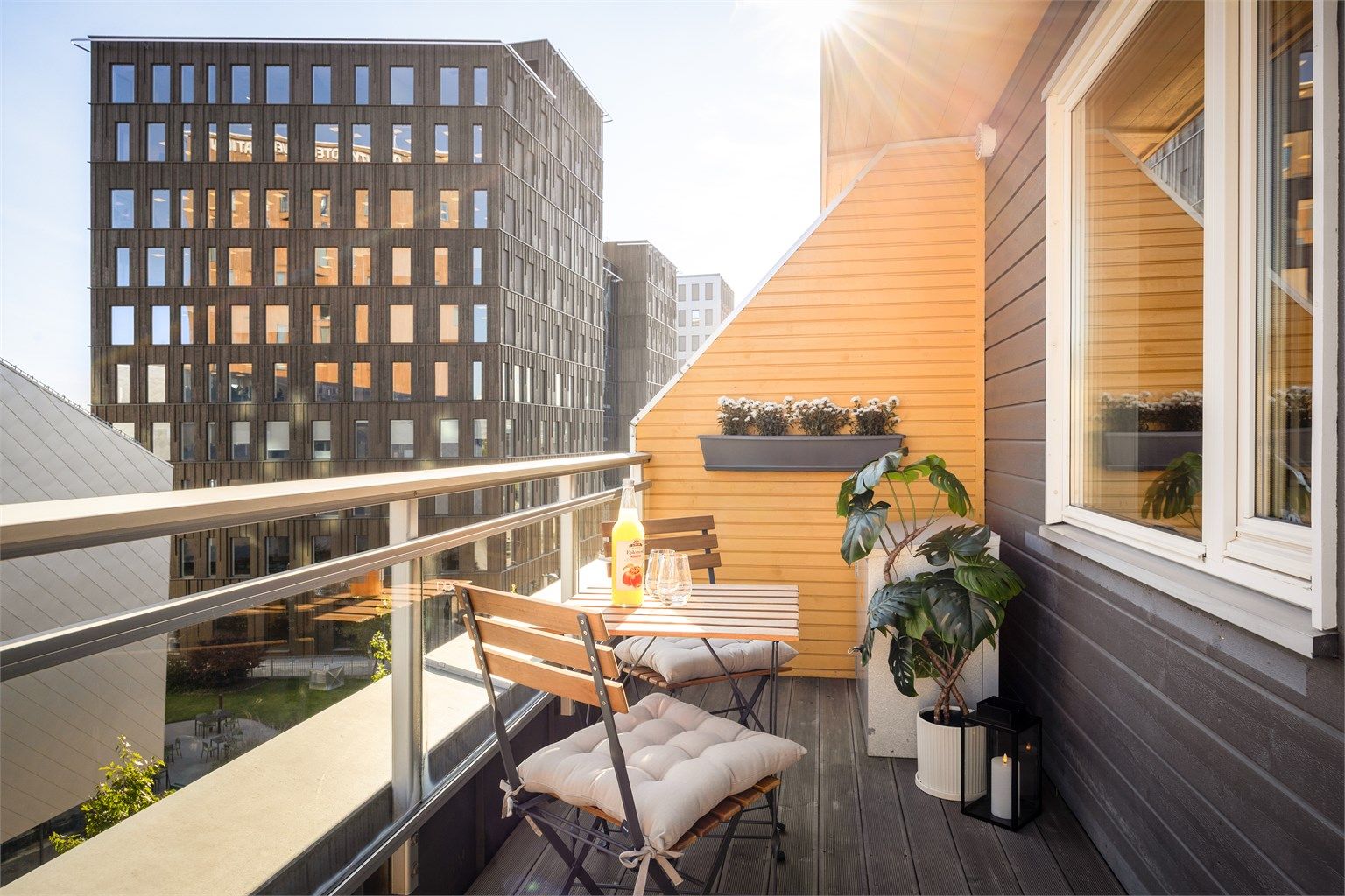 Balkong med terrassebord (2025) og rekkverk av stål samt glass.
