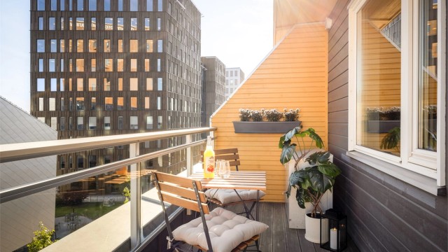 Balkong med terrassebord (2025) og rekkverk av stål samt glass.