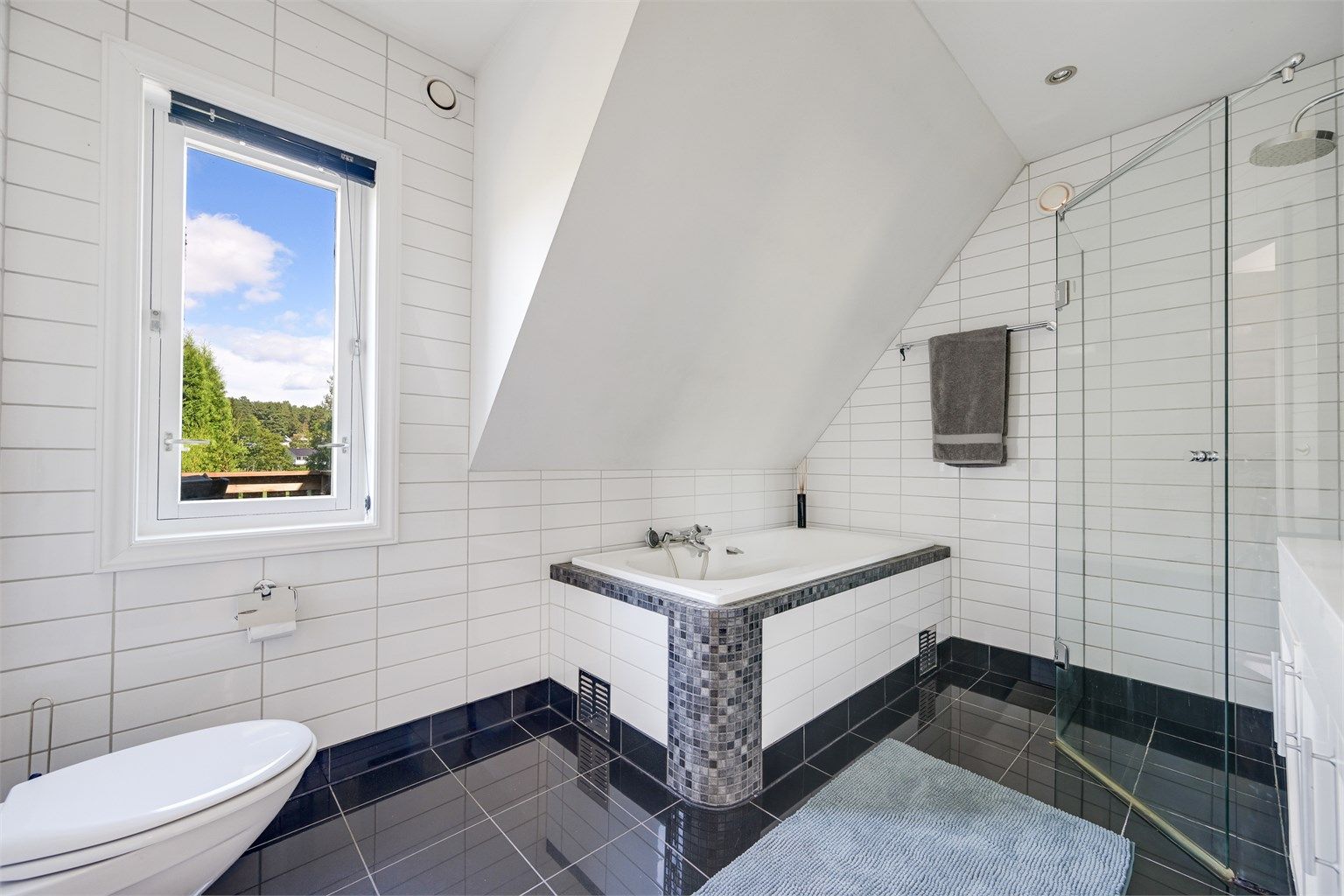 Lyst og romslig bad med flislagt gulv og vegger. Det er varmekabler i gulv med ny gulvtermostat og spotter i taket. 