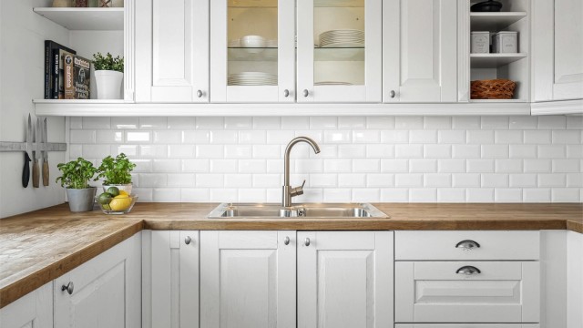 Praktisk nedfelt dobbel oppvaskkum og fliser på veggen mellom benk og overskap.