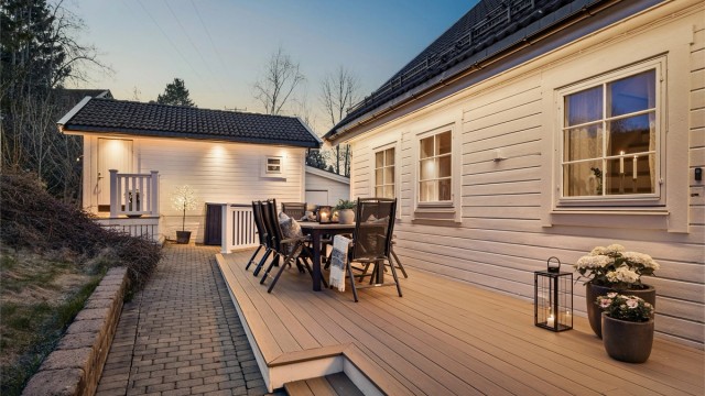 Asfaltert adkomst til garasjen fra 2024 og belegningsstein langs deler av husveggen.