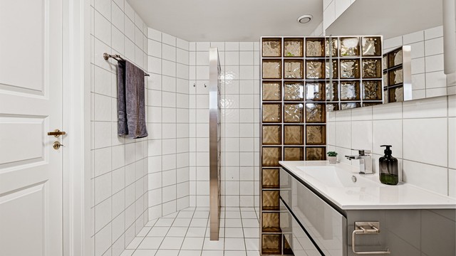 Badet har en romslig dusjnisje med glassvegg, vegghengt servantinnredning og gulvstående toalett.