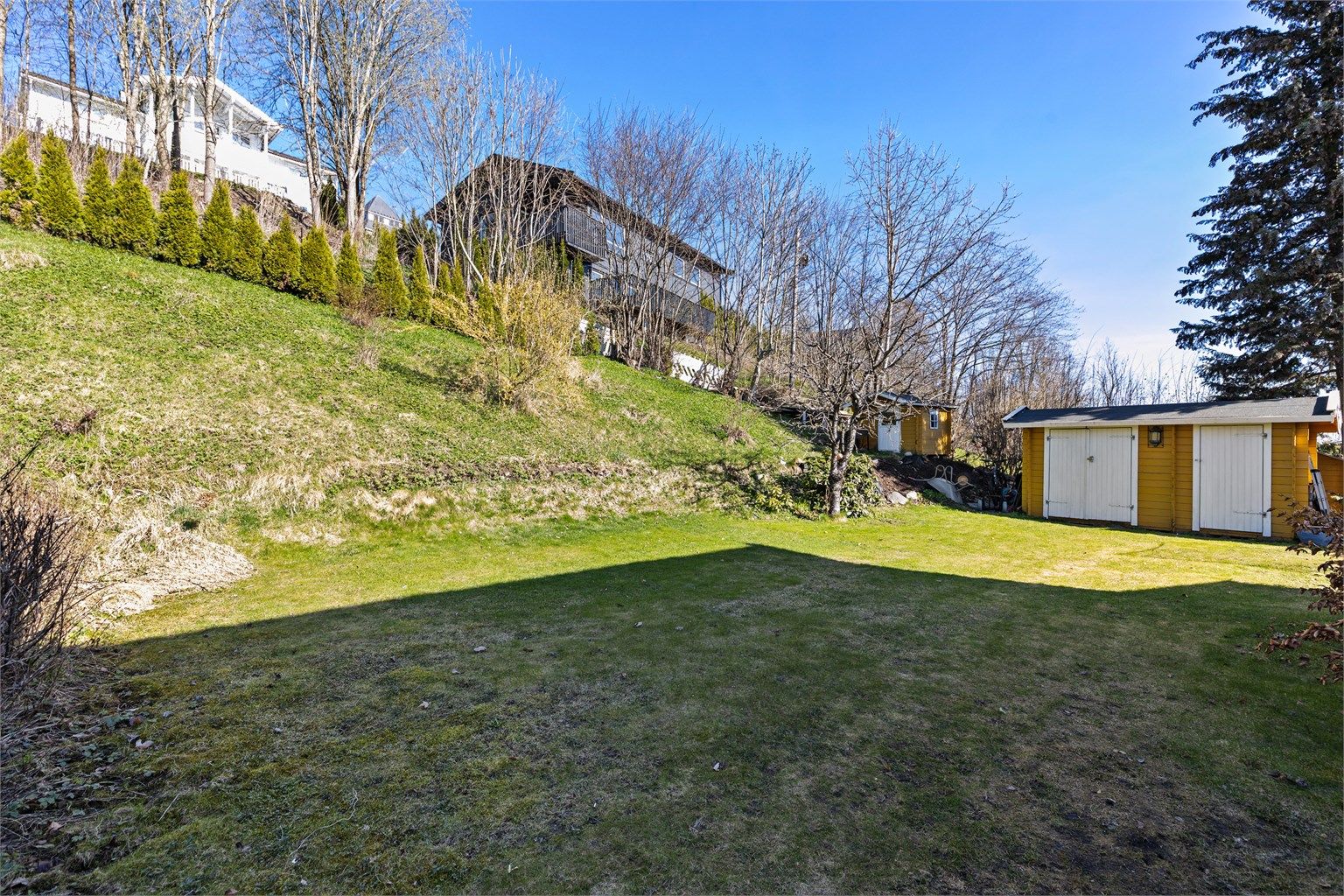 Boligen har en hyggelig hage med diverse beplantning og utvendig bod.