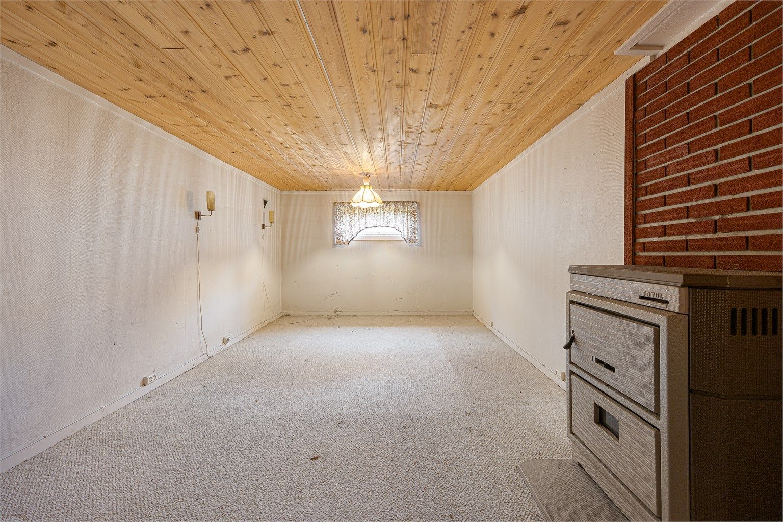 Stort, innredet rom i kjelleren med en kombinert ved- og oljekamin. Takhøyden i kjelleren er målt til ca. 2,00-2,05 meter.