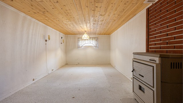 Stort, innredet rom i kjelleren med en kombinert ved- og oljekamin. Takhøyden i kjelleren er målt til ca. 2,00-2,05 meter.