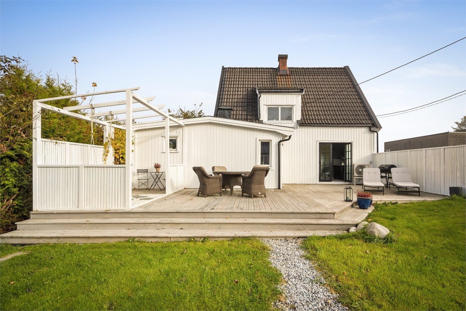 Stor terrasse i trekonstruksjoner med levegger, pergola og god plass til utemøbler.