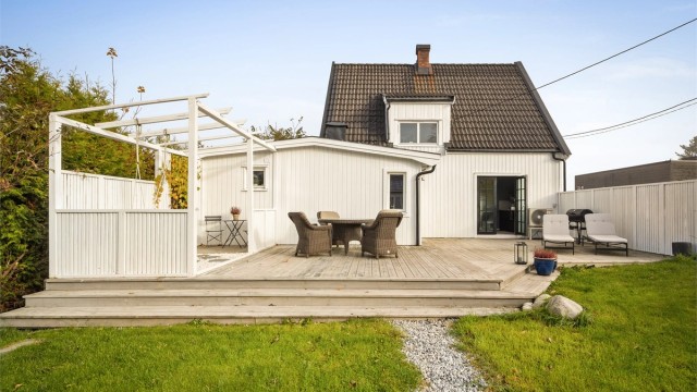 Stor terrasse i trekonstruksjoner med levegger, pergola og god plass til utemøbler.