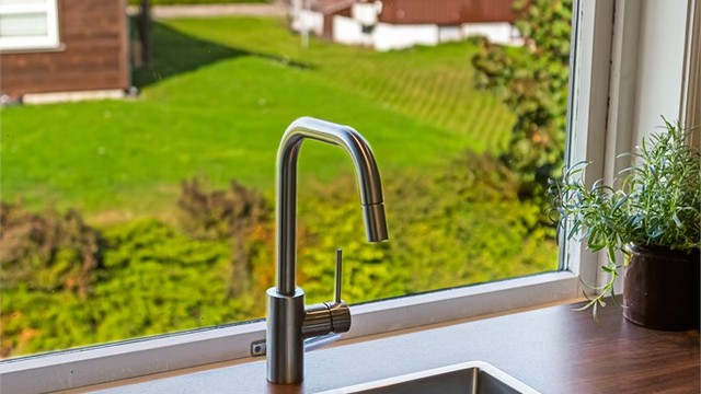 Nedfelt oppvaskkum i rustfritt stål plassert ved kjøkkenvinduet.