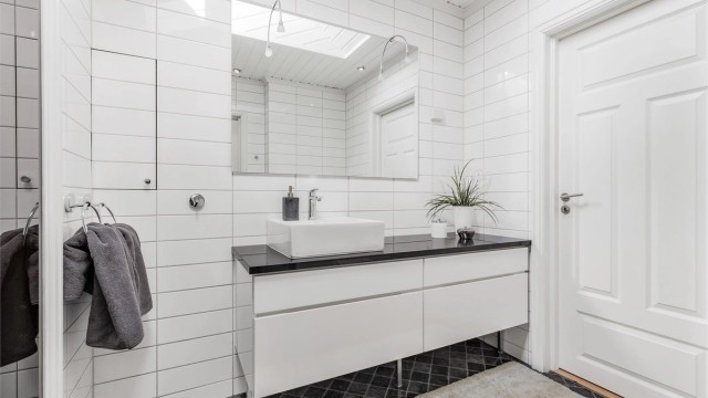 Baderom fra byggeår. Flislagt gulv med gulvvarme. Flislagte vegger. Trekledning og fliser i himling. Vegghengt servantinnredning. Speil med overlys.