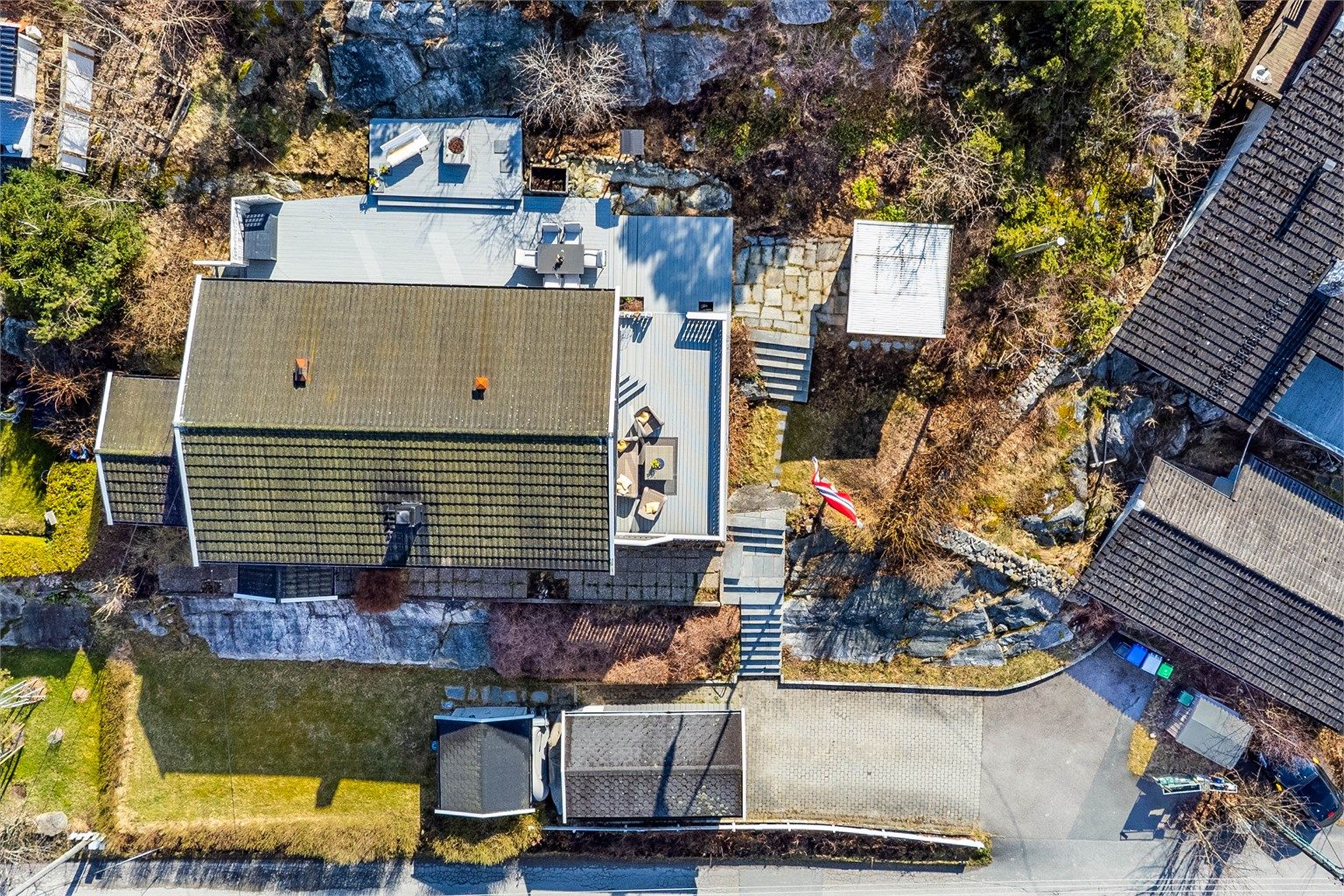 Tomten er eiet og angitt til 857 kvm., her sett i fugleperspektiv med vest mot nedre bildekant. I garasjen og oppkjørselen er det oppstillingsmulighet for tre-fire biler.