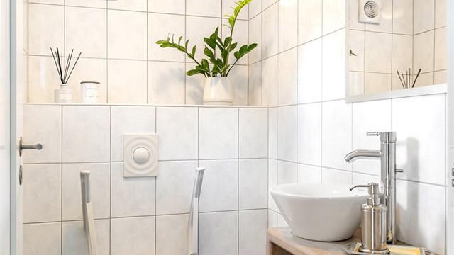 Praktisk toalettrom i første etasje med flislagte overflater og mekanisk avtrekksvifte.
