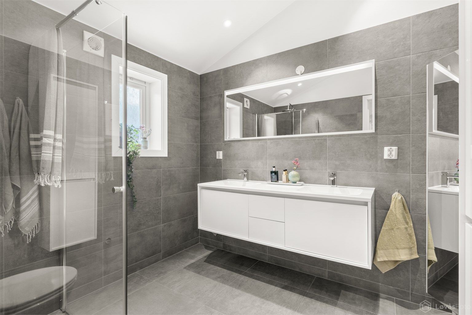 Moderne en-suite bad fra 2016 med heldekkende dobbelservant og flislagte overflater.
