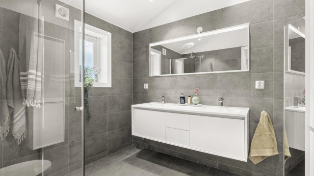 Moderne en-suite bad fra 2016 med heldekkende dobbelservant og flislagte overflater.
