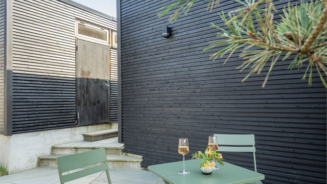 En liten, skjermet uteplass ved inngangspartiet, belagt med naturskifer.