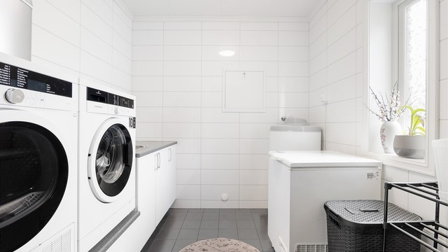 Arbeidsbenk, utslagsvask og dedikert plass til både vaskemaskin og tørketrommel i arbeidshøyde gjør vaskerommet bruksvennlig.