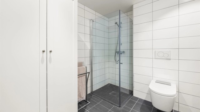 Badet har dusjhjørne med foldedører av glass.