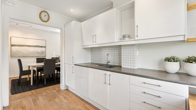 Kjøkkeninnredningen har slette fronter og nedsenket himling med downlights.