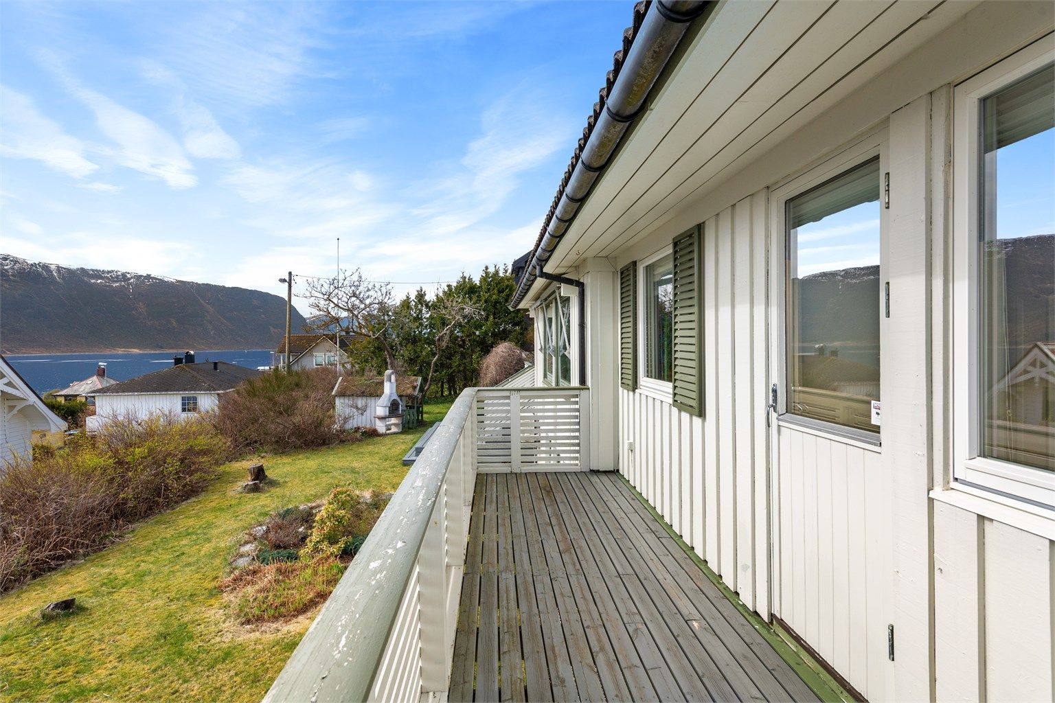 Verandaen strekker seg langs deler av fasaden mot sør og er bygget med et rekkverk i treverk.