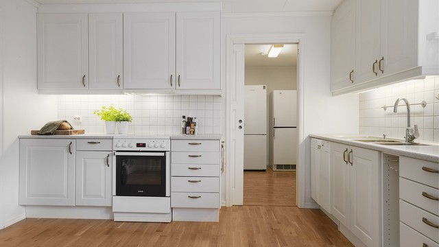 Kjøkken med malte mdf-fronter, laminat benkeplate og adkomst til grovkjøkken.
