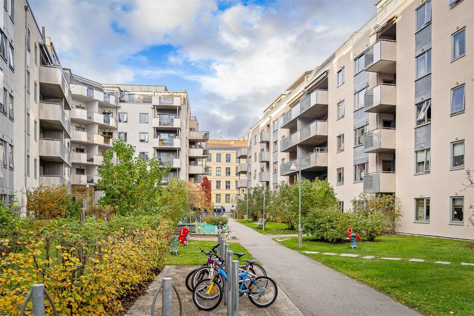Pent opparbeidet bakgård med gressplen, beplantning og felles sykkelparkering 