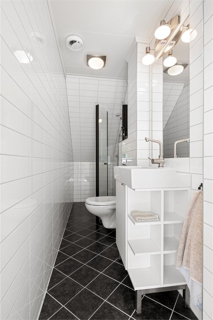 Badet er utstyrt med vegghengt toalett, servant og dusjnisje med glassvegg.