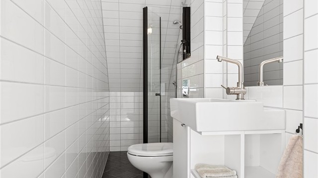 Badet er utstyrt med vegghengt toalett, servant og dusjnisje med glassvegg.