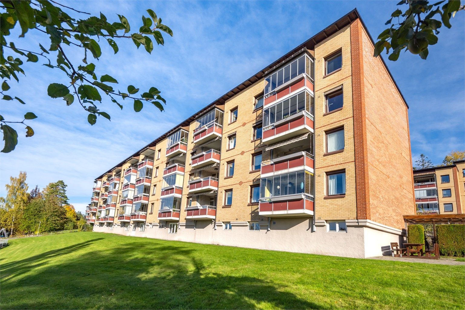 Velholdt boligblokk i Ulsrud Borettslag med teglsteinsfasade og store grøntområder.