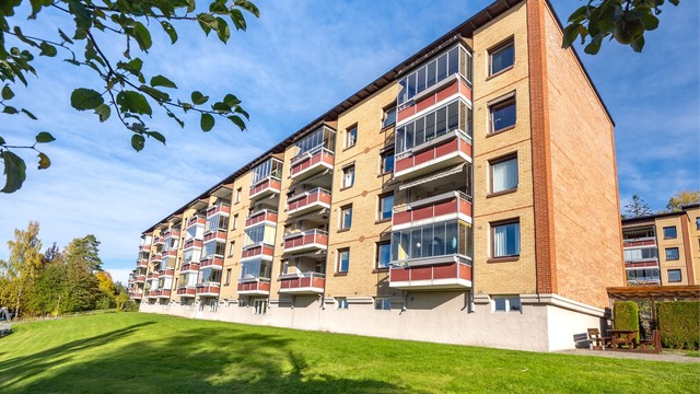Velholdt boligblokk i Ulsrud Borettslag med teglsteinsfasade og store grøntområder.